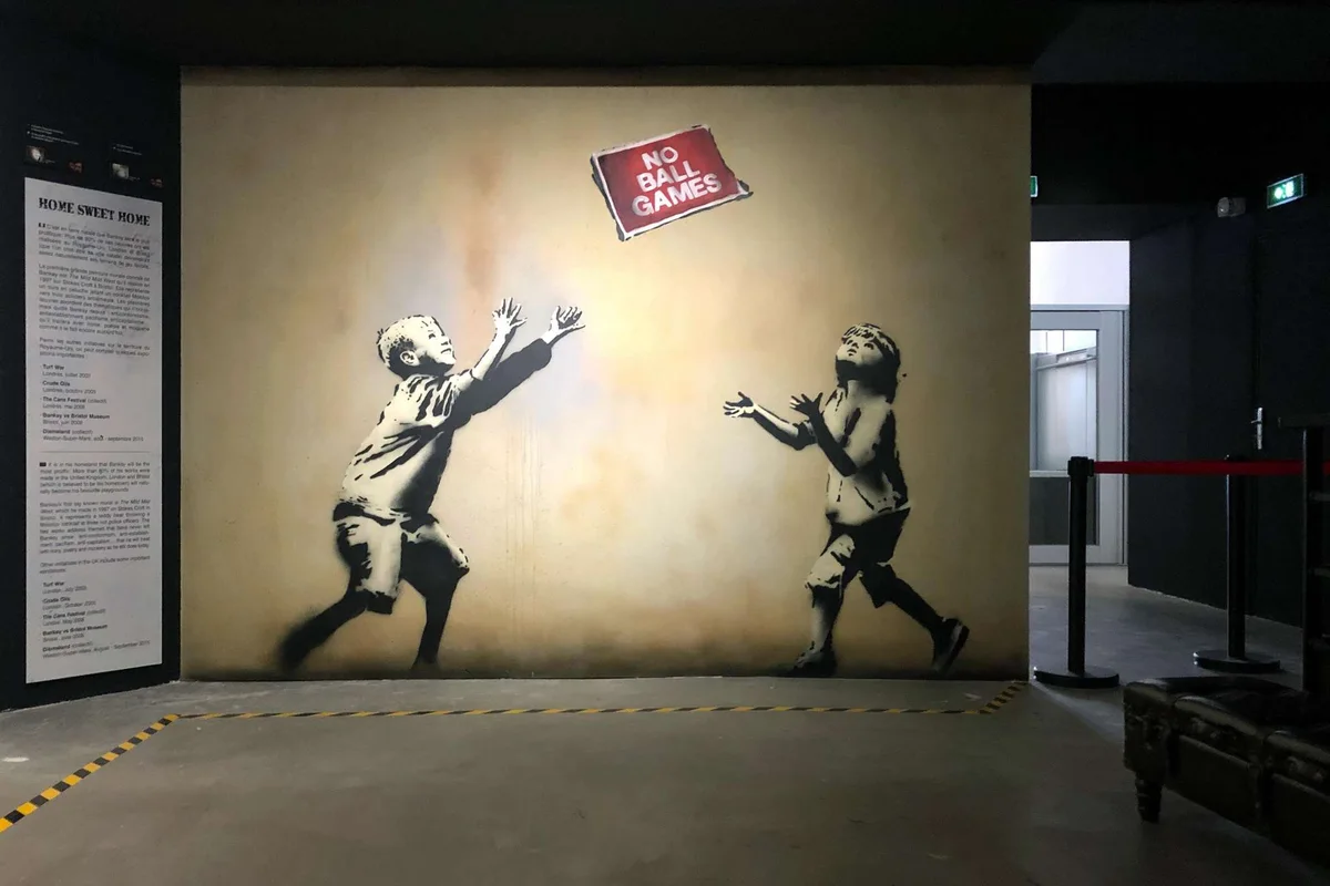A reproduced Banksy stencil on the wall of The World of Banksy immersive experience, a museum in Paris