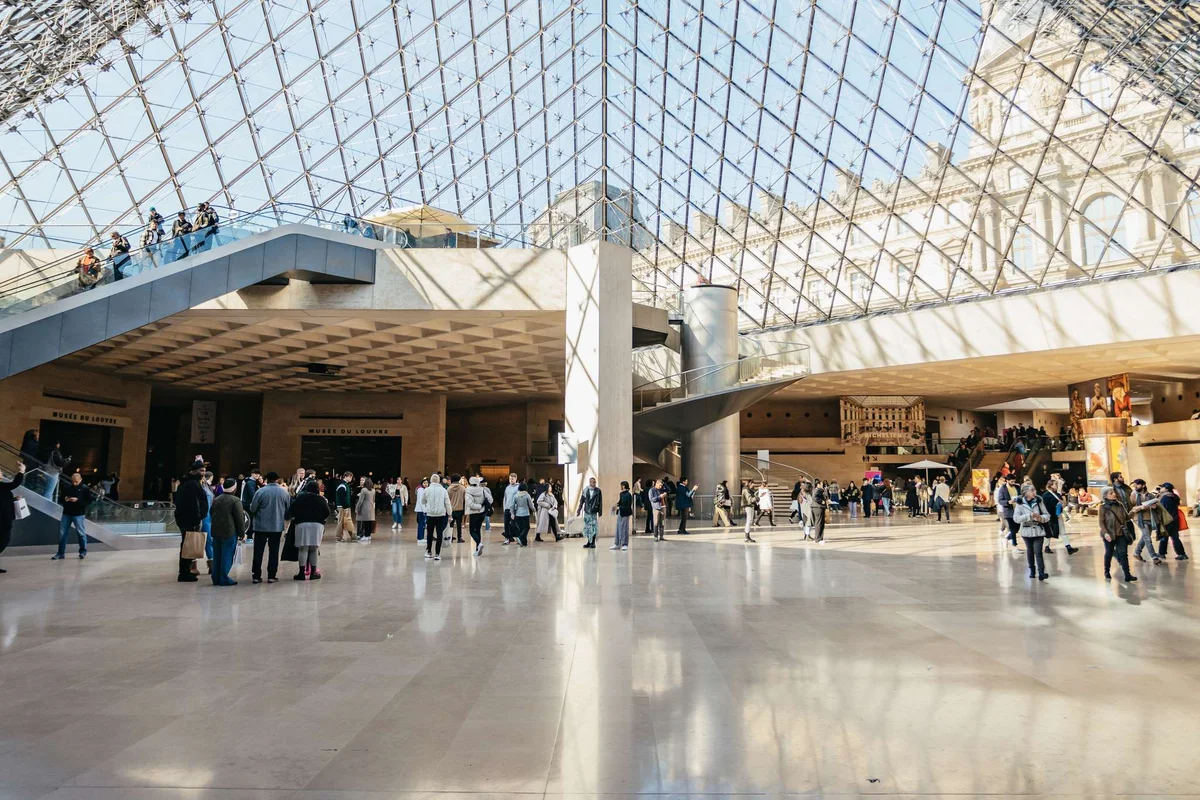 Visitors under the glass pyramid entrance hall of the Louvre, the most visited of the museums in Paris
